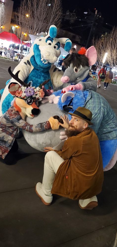 Five people solemnly pondering a round fursuit tummy