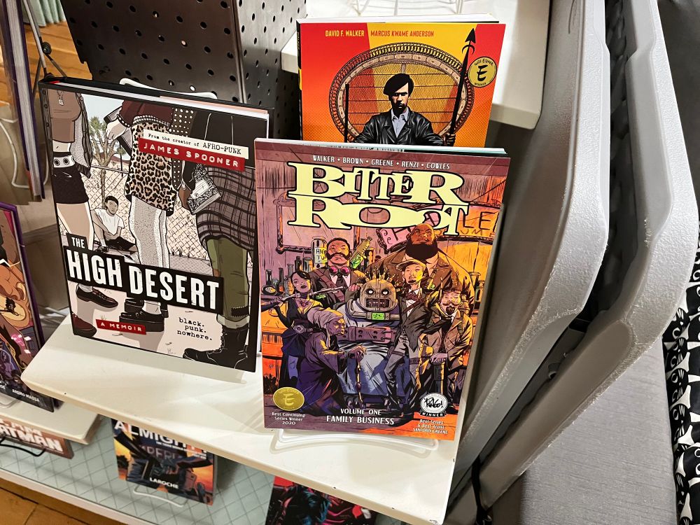 A bookshelf displaying The High Desert, Bitter Root vol 1: Family Business, and The Black Panther Party