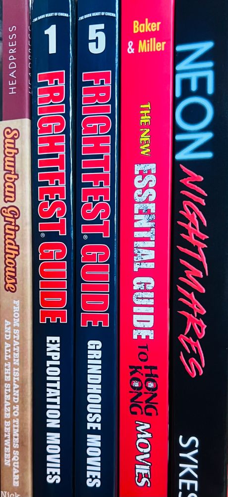 A stack of film guides, including Suburban Grindhouse, Frightfest Exploitation & Grindhouse Guides, Essential Guide for Hong Kong, & Neon Nightmares