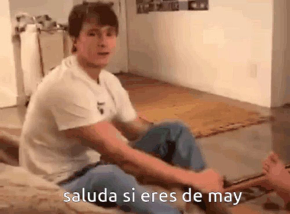 a man is sitting on the floor with his legs crossed and the words saluda si eres de may written on the bottom .