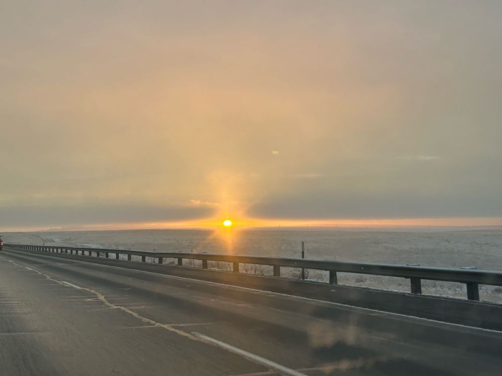 A photo of the distant sunrise above a paved road. In the background there are frosty plains of eastern Oregon 