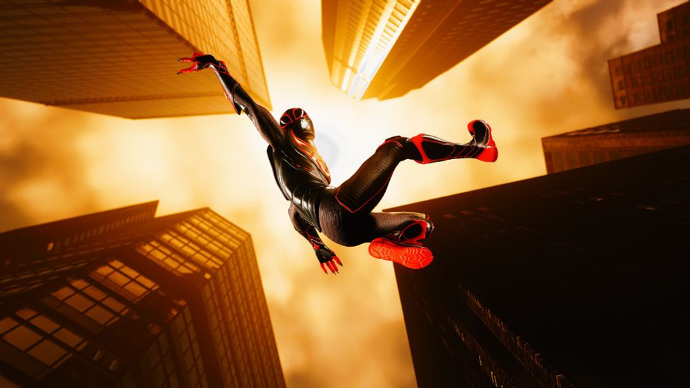 A screenshot from the video game Spider-Man 2 for the PlayStation 5. Spider-Man is seen mid-swing, zipping past buildings that tower into the distance. The sun shines above him, highlighting him with light in against his dark surroundings.