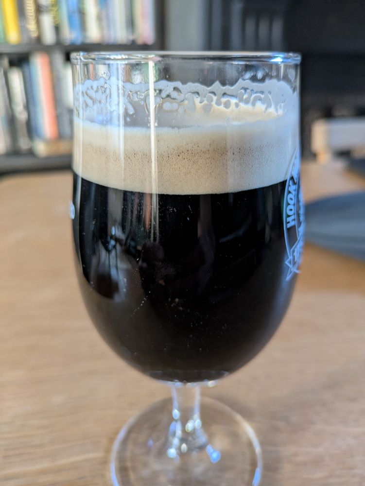 Image of a glass of dark beer with a white foamy head