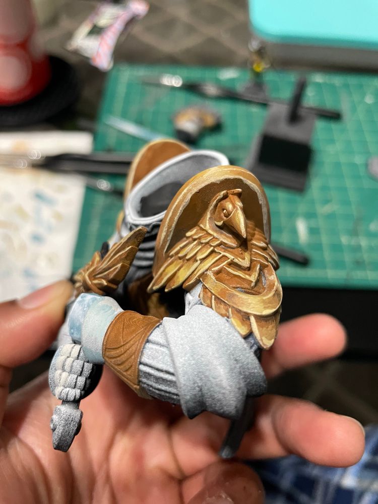Shoulder armor with a bird face on it painted in a orange yellow to make it look like metal