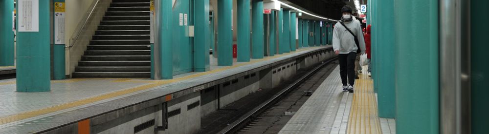 A close-up  of a person walking on a subway platform in Japan.