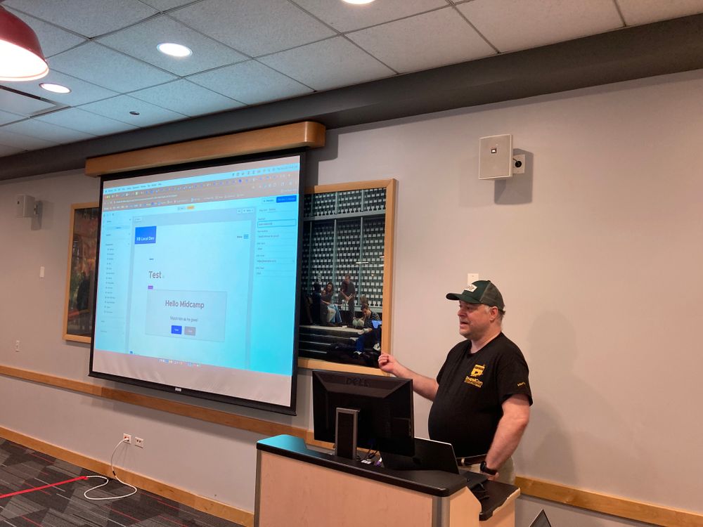 User cosmicdreams in front of a podium pointing at a screen demoing a web sitr