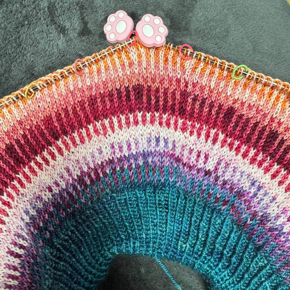 The yoke of a knit sweater in progress, in rainbow stripes 