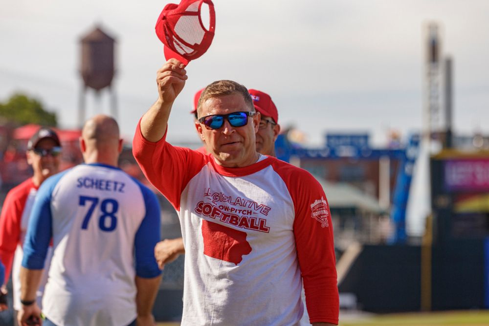 Iowa State Senator Mike Boussalot waves his hat at his opponents as the game concludes