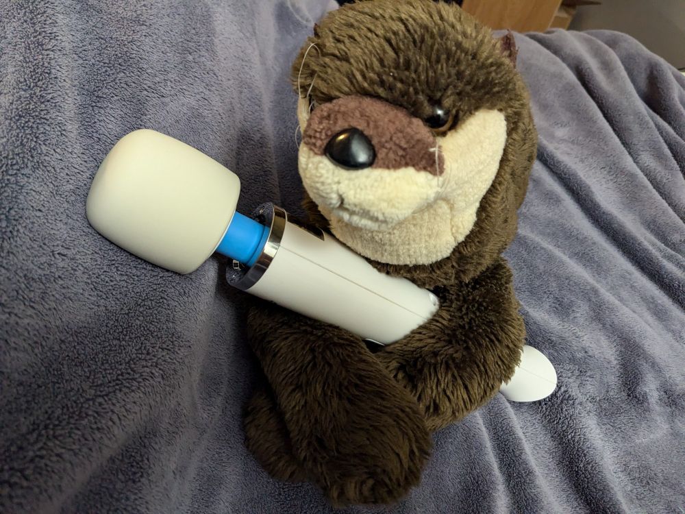Otter plush holding Magic Wand vibrator