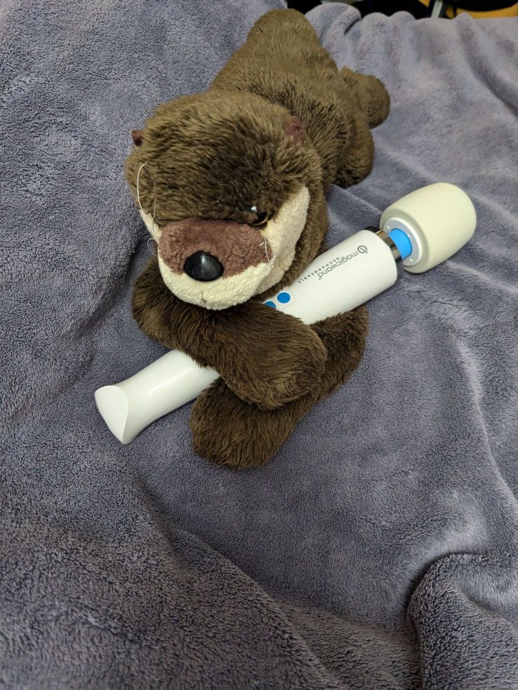 Otter plush holding Magic Wand vibrator