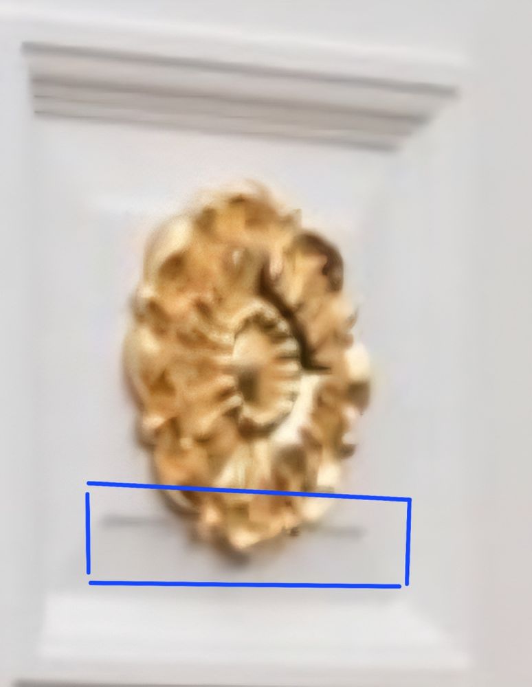 Close up of gold coloured moulding stuck to a door panel overhanging the flat area. 