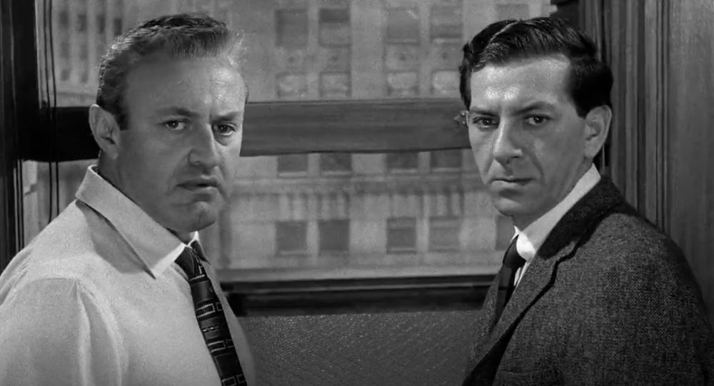 A still from 12 Angry Men (1957): Two men pause their argument and turn  towards the camera 