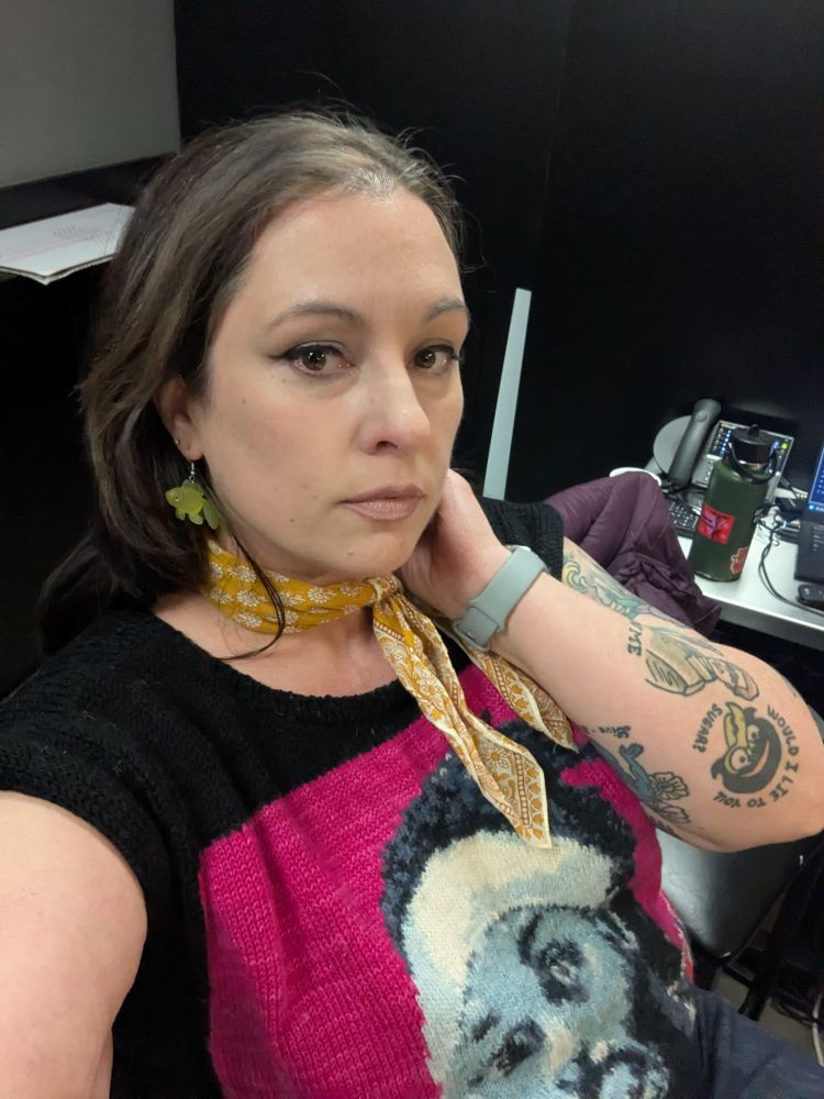 A woman wearing a colorful sweater and neckerchief 