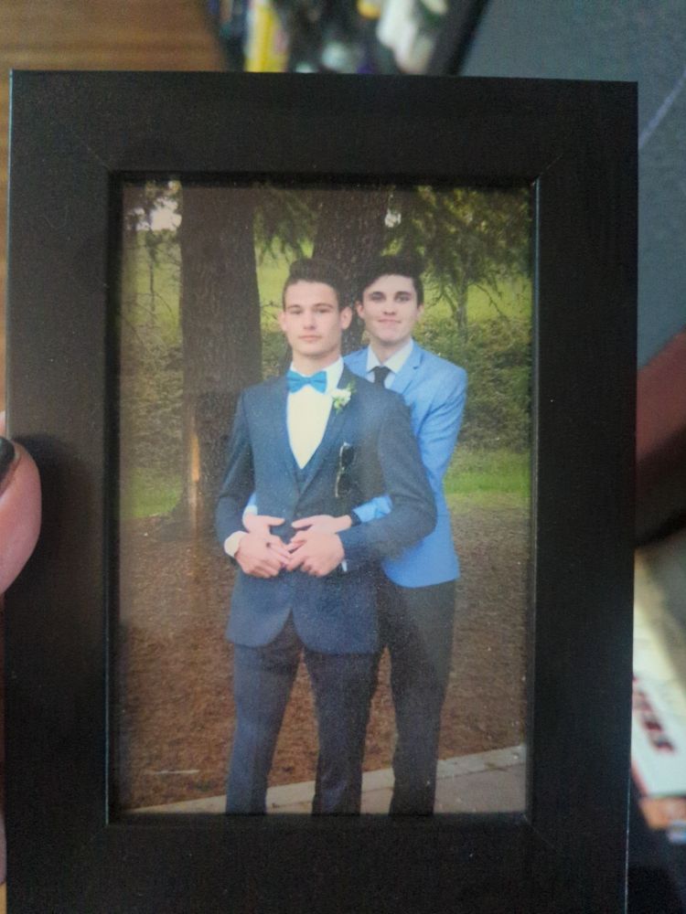 2 teenage boys posing in prom outfits