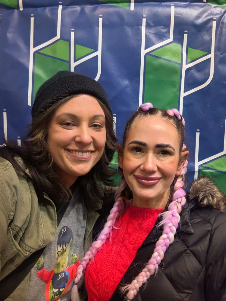 Gina and Emily in front of a "raise the chairs" backdrop