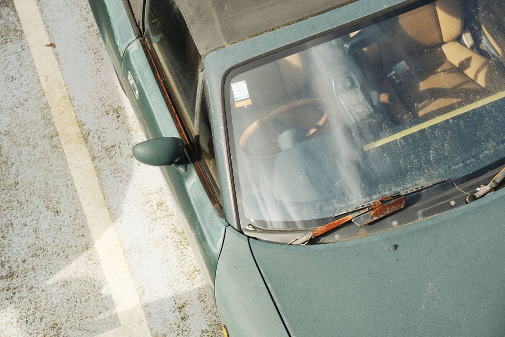 A fragment of an old rusty car in faded green colour