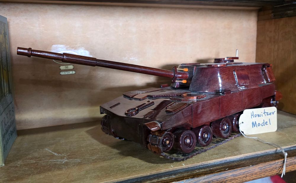 A wooden model of a Howitzer tank in a vintage decor booth. 