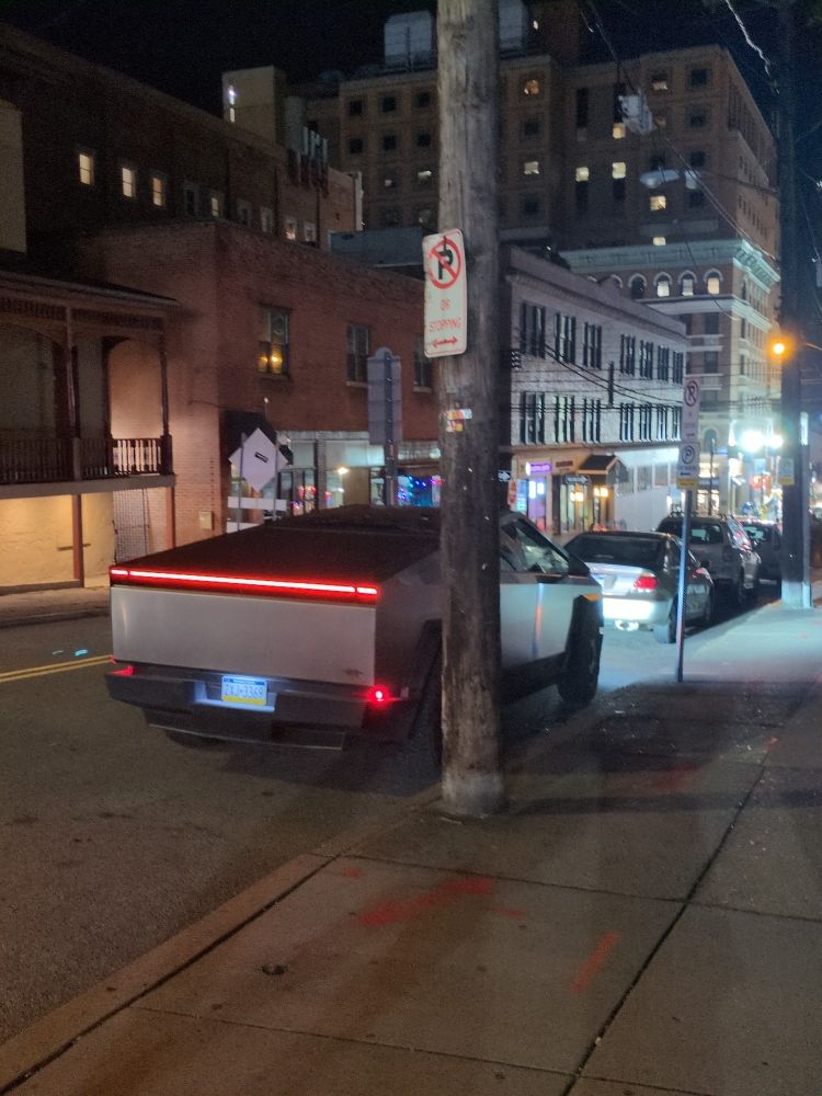 a cybertruck on a city street at night, seen from behind