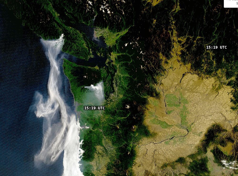 This is a satellite image of the west coast of North America, showing Vancouver Island at the top and the coast of Washington and Oregon. White streaks of smoke wisp down from Vancouver Island. A smaller smokey area is visibile in the center from a fire in western Washington.