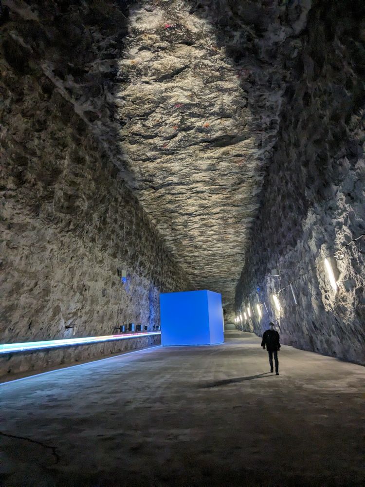 Big cavern cut into a salt dome, big blue cube installation in the back