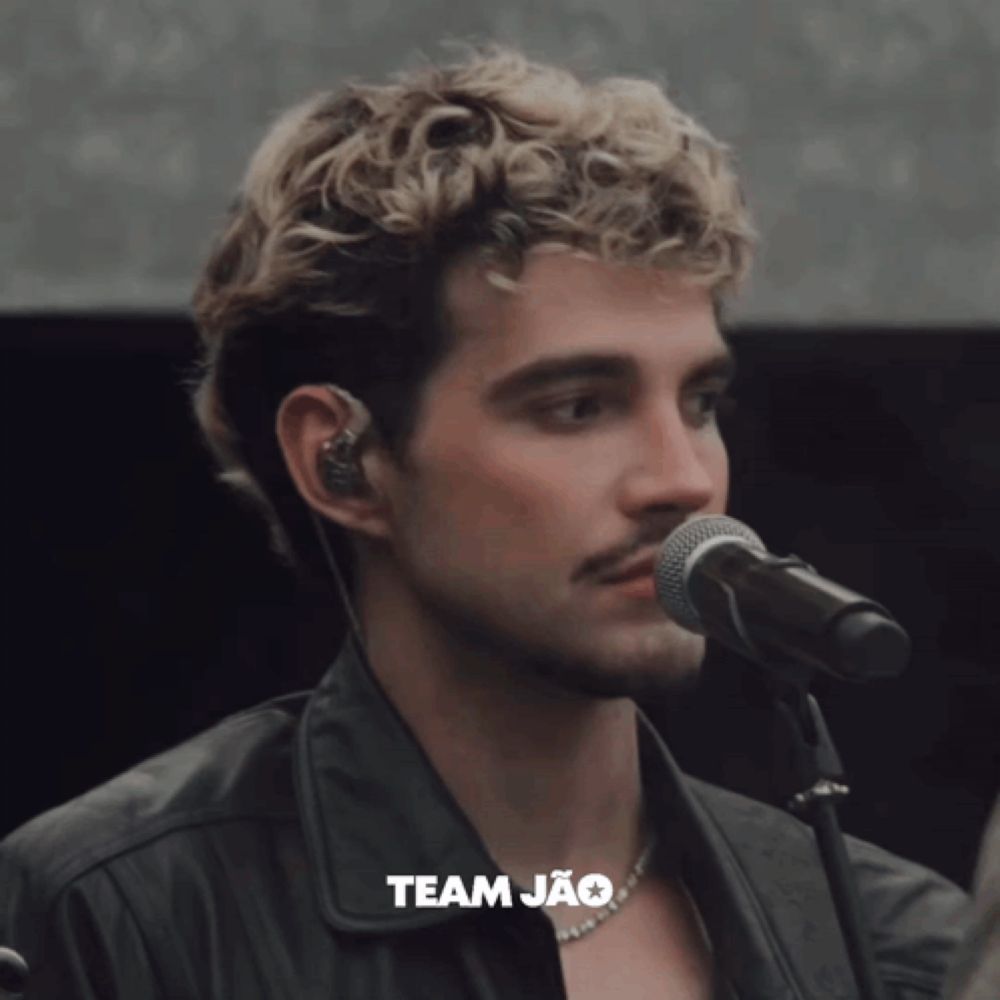 a close up of a man singing into a microphone with team jao written on the bottom