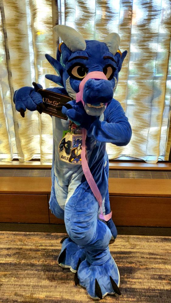Akuren holding an invitation to the Gala at Furry Migration.