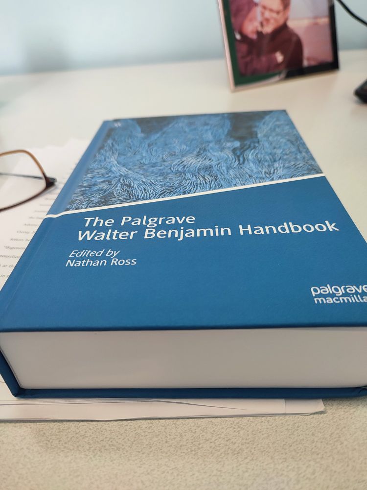 An angled photograph of The Palgrave Walter Benjamin Handbook on a desk, showing the cover and the thickness of the book