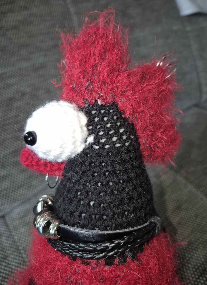 Huhn von der Seite, ein Zottiger roter Iro und zwei Ringe in den Haaren 