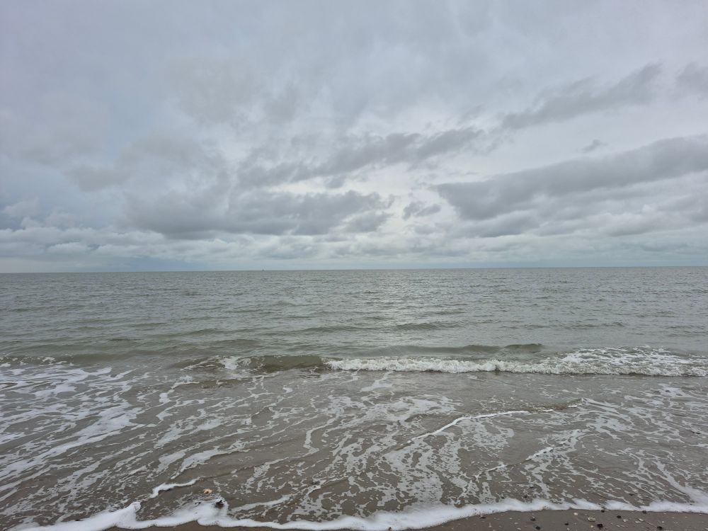 Blick aufs Meer, tiefhängende graue Wolken, aber die Sonne blinzelt durch