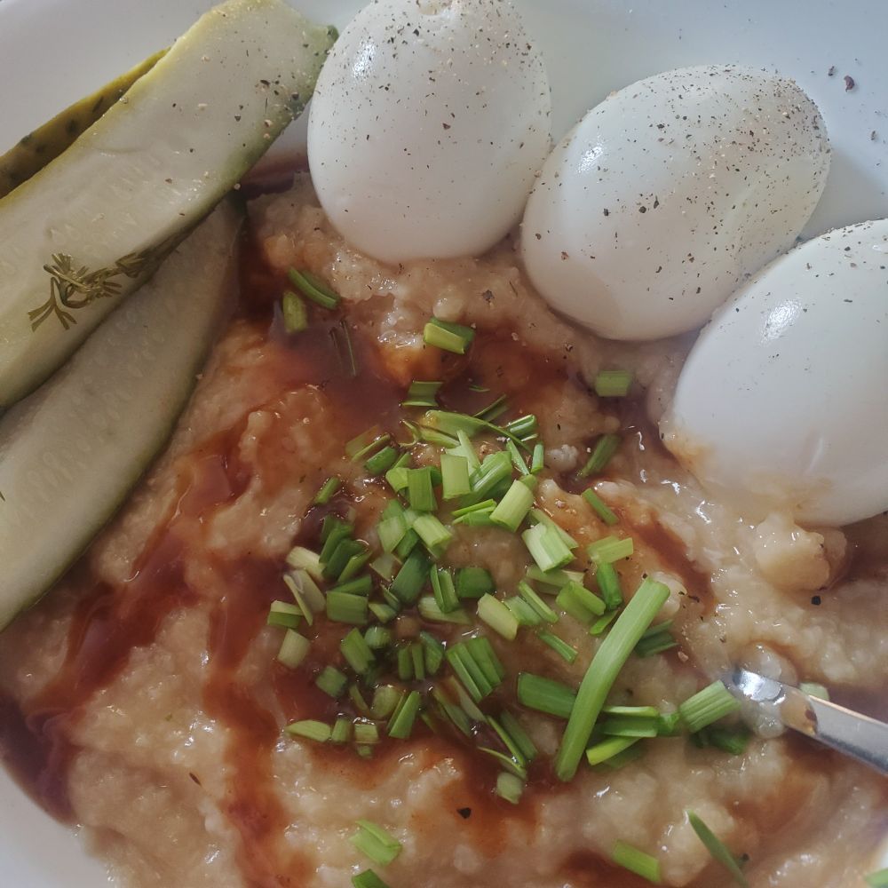Jook with sauce, garlic greens, pickles and eggs.