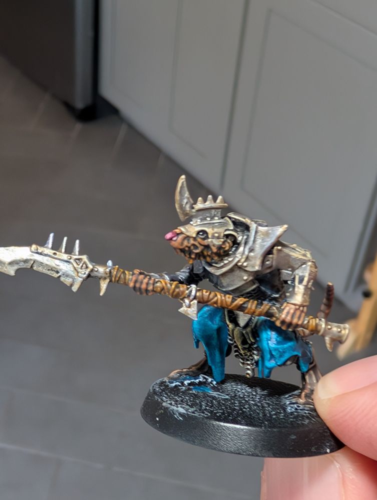The GW store's model of the month from December 2024. A bipedal rat guy holding a spear. His fur is brown, tunic is blue, and armour is a ruddy silver. He has a pink button nose, naturally.