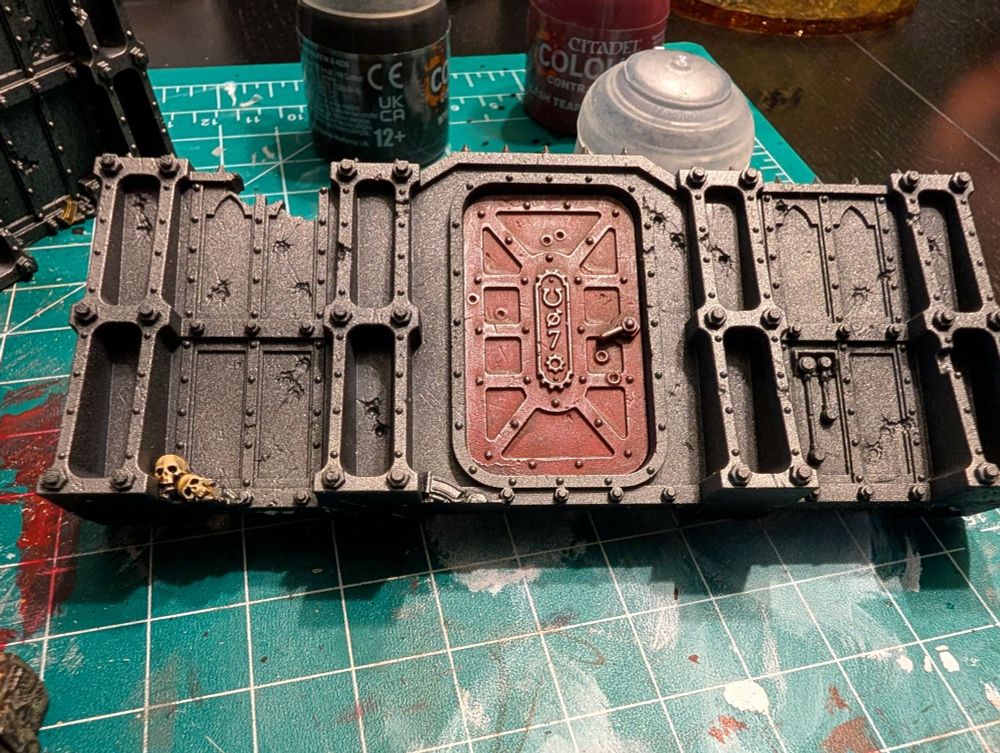 Various pieces of the Compound Siege (ruin walls, boxes, etc.) terrain set painted silver with various details of red and gold. 