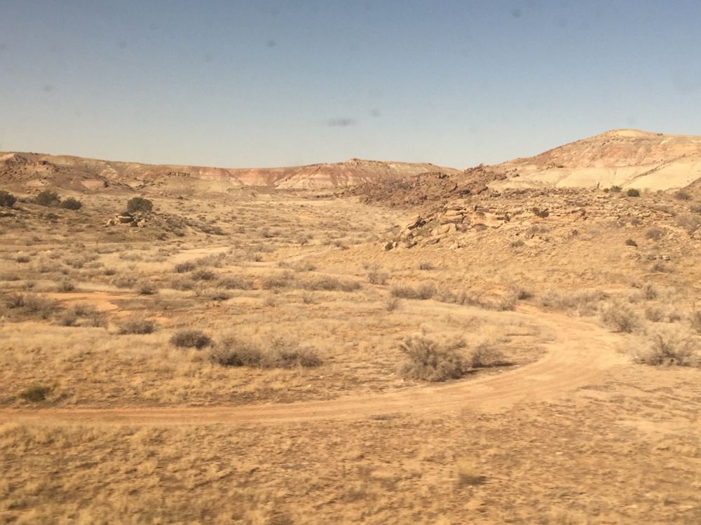 A barren dry river basin with a dirt road winding through it.