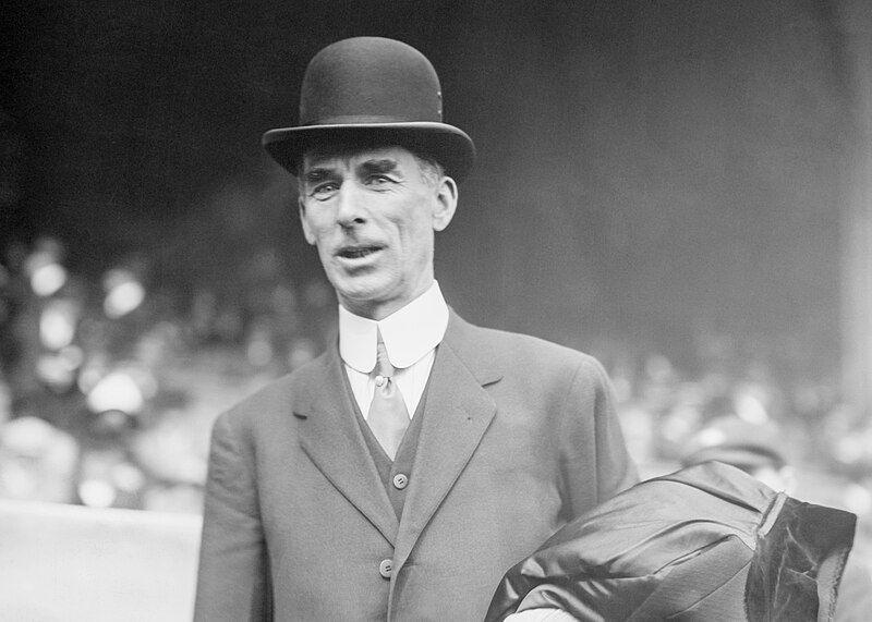 Baseball manager Connie Mack in 1911, dressed in a three-piece suit, with a high paper collar and a tie with a pearl pin, plus a tall bowler hat