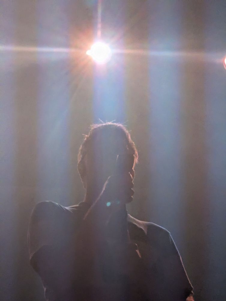 LCD Soundsystem live in concert, a silloieutte in front of a stage light
