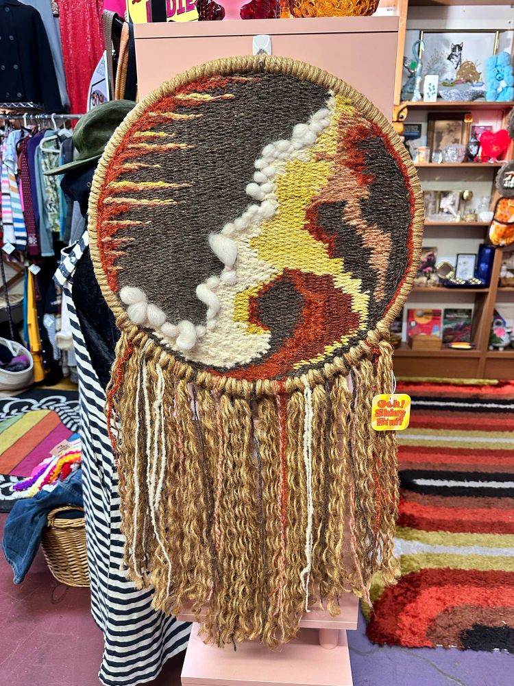 A vintage round woven art piece with long fringe