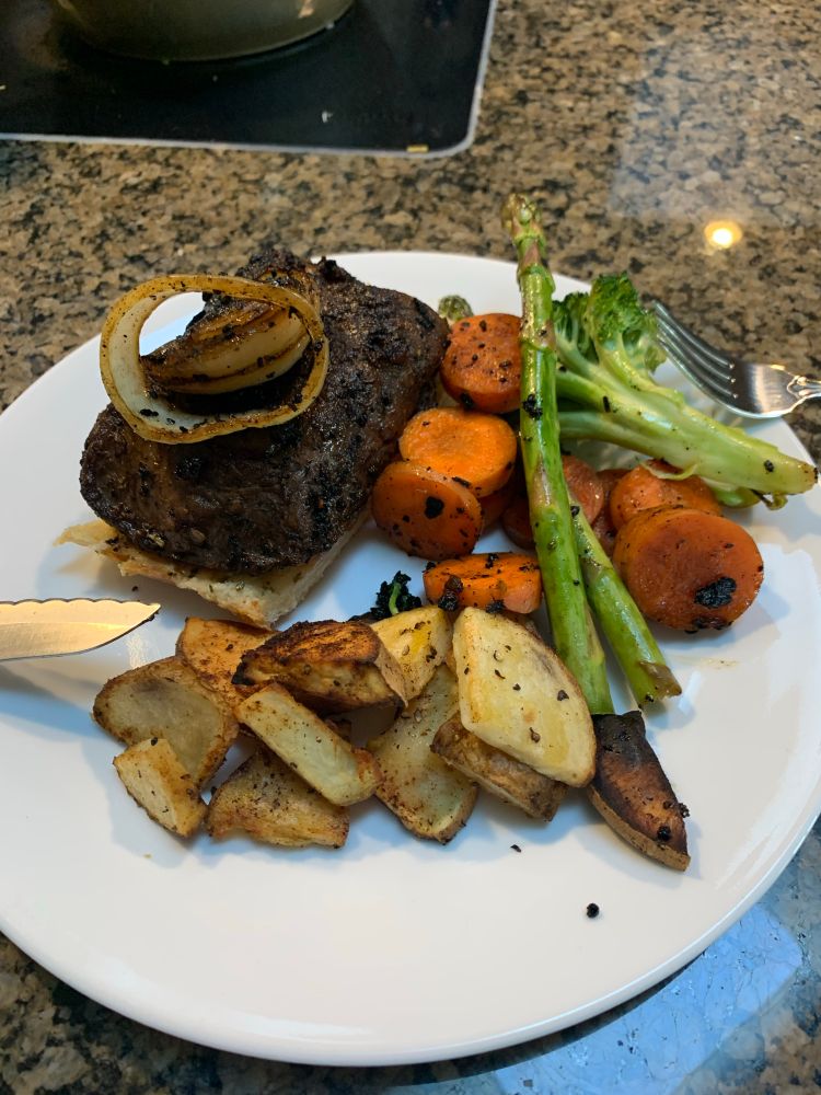 A plate of the previous food mentioned. The sirloin steak in on top of a slice of garlic bread and a few rings on the onion are on top.