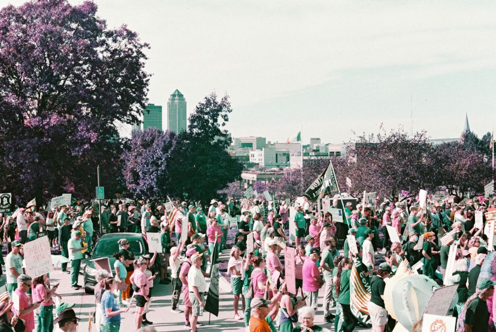 photo taken from the capital building looking back toward downtown des moines, with various protesters and signs