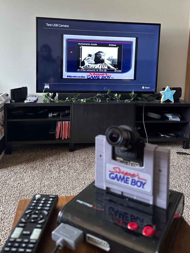 image depicting the setup in order to use a gameboy camera as a camera device on nintendo switch 2. aftermarket cartridge with a lens, super gameboy into a third-party super nintendo, sending video into an hdmi converter, and being captured with a usb capture device on the switch 2 dock