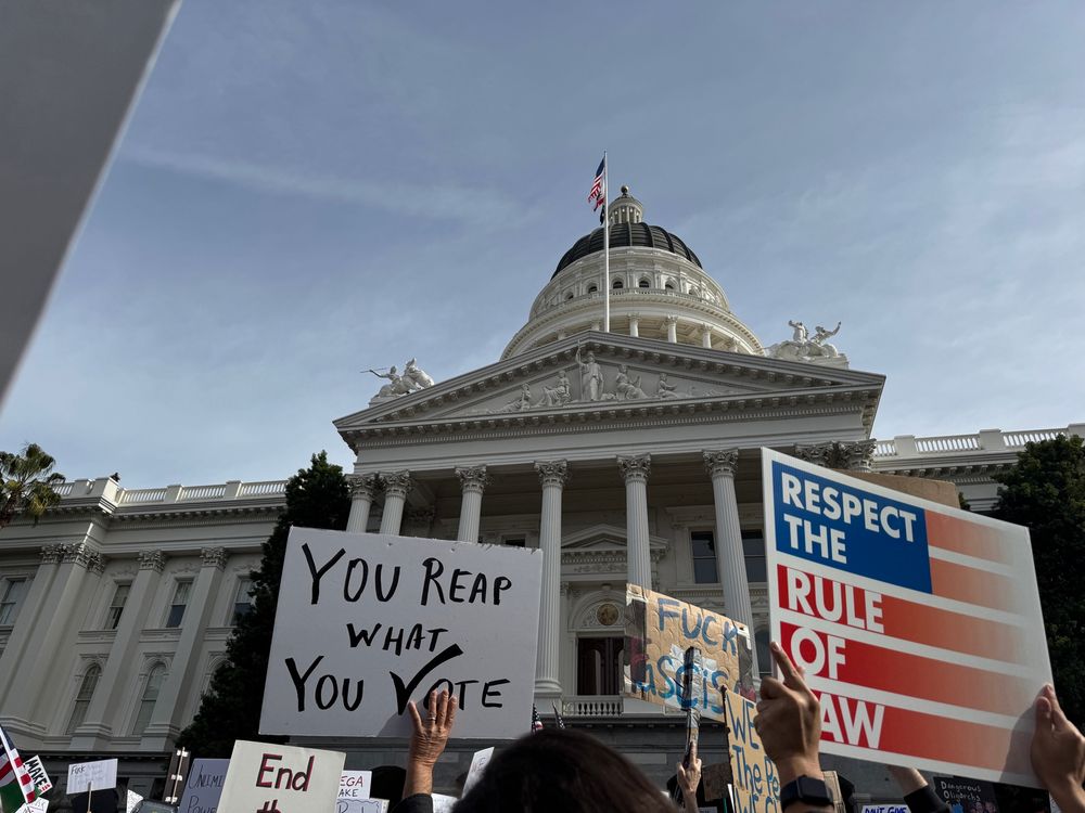 California State Capitol building with posters written as “You Reap What You Vote” “Respect the Rule of Law” “Fuck Fascism” 