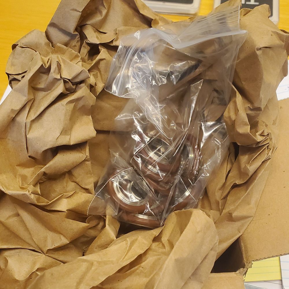 Brown O-rings in plastic bag over brown packing paper and cardboard box