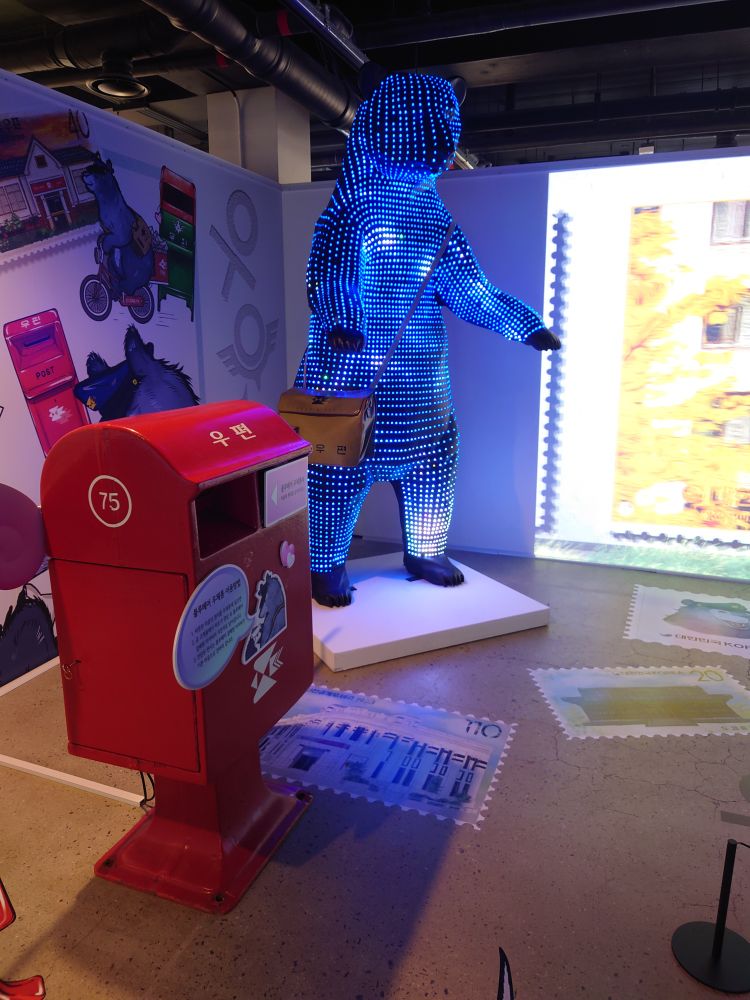 À l'Exposition philatélique de Corée de juillet 2024, à Séoul, une boîte aux lettres spéciales et le facteur Ours Bleu (un ours tapissé de diodes luminescentes bleues) proposent d'envoyer des messages qui seront reçues dans un an.