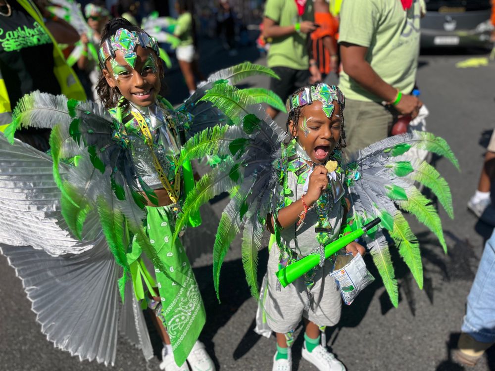 Two kids wearing green feathers at Notting Hill Carnival