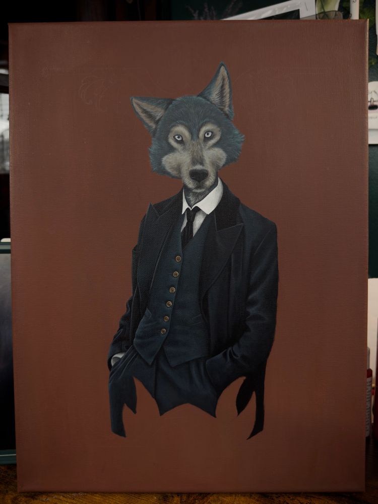 A picture of a painting propped on a desk. The painting is partially finished with a human-like figure with a wolf for a head wearing a black/navy blue suit and coat. The wolf humanoid is centered on a milk brown colored background. 
