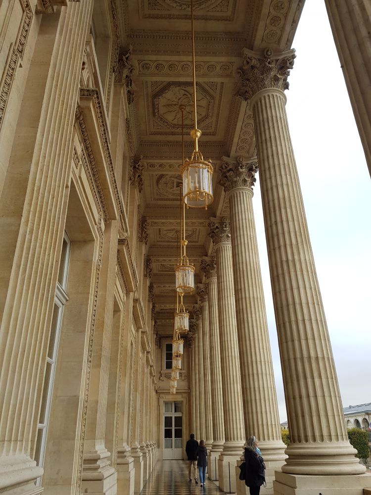 "Balcon -Galerie" sur la façade  de l'hôtel de la Marine . A droite colonnes style corinthien, à gauche, grandes portes fenêtres s'ouvrant sur la grande salle de réception. Plafond à caisson d'où pendesnt des lanternes cylindriques aux armatures dorées. Ciel laiteux sur la place de la Concorde