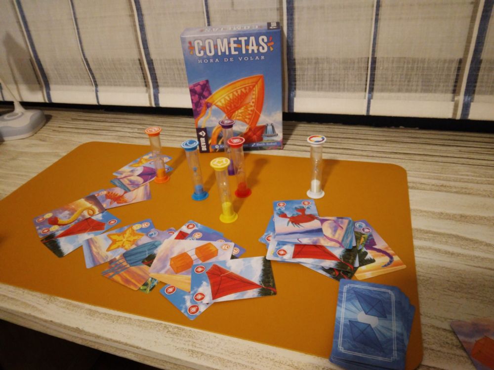 Juego de mesa Cometas con sus componentes, cartas y relojes de arena.