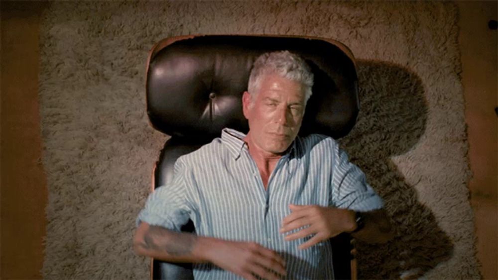 a man in a blue and white striped shirt is laying in a chair