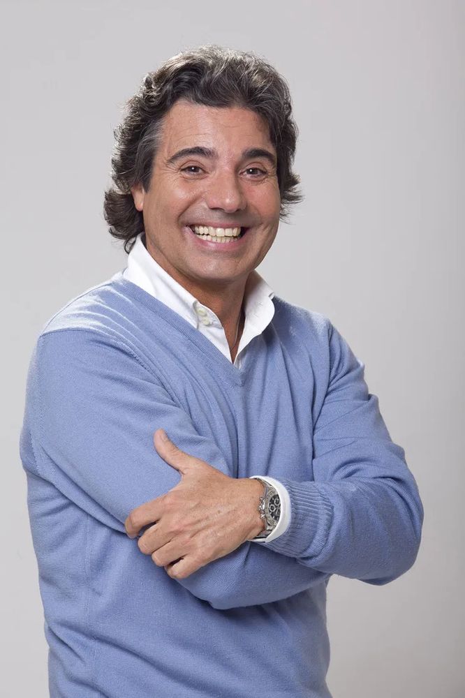 João Kleber, homem branco de roupa azul e braços cruzados sorrindo.