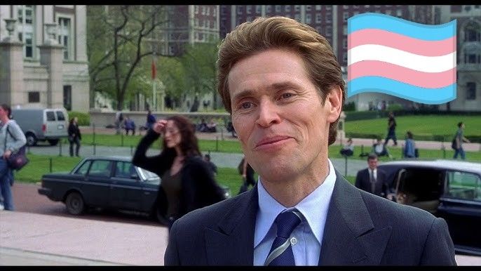 Norman Osborne with a trans flag behind him 