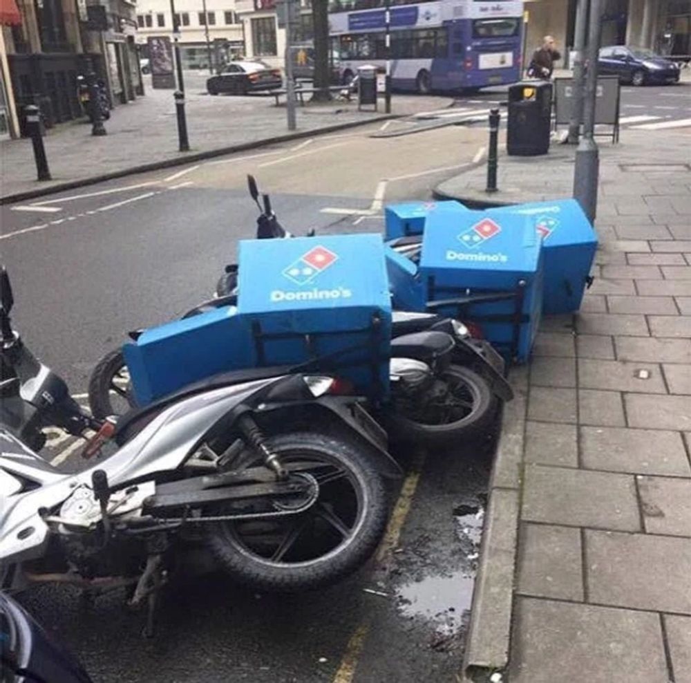 Dominos pizza bikes in a row, all collapsed on each other like a line of fallen dominos
